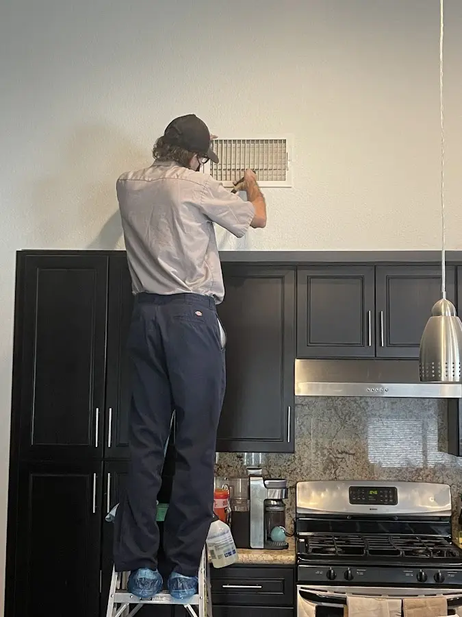 Technician inspecting an air vent during HVAC service in Gold Canyon